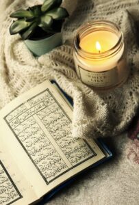 photo of quran beside lighted candle