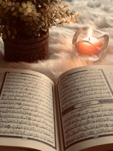photo of an open book beside red lighted candle