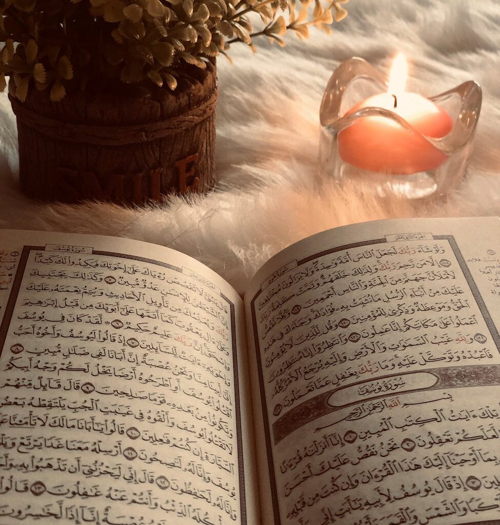 photo of an open book beside red lighted candle
