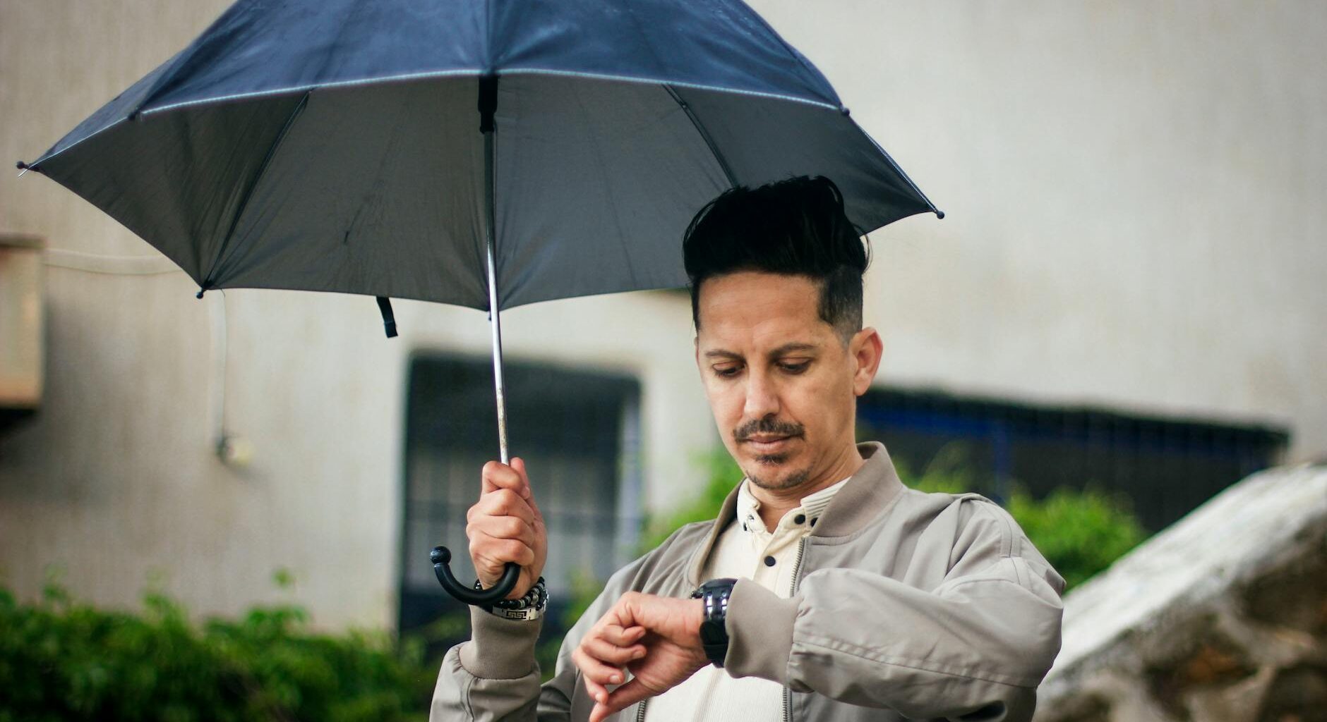man with umbrella checking watch outdoors in algeria