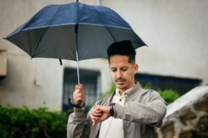 man with umbrella checking watch outdoors in algeria