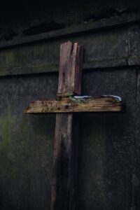 a broken wooden crucifix leaning on concrete
