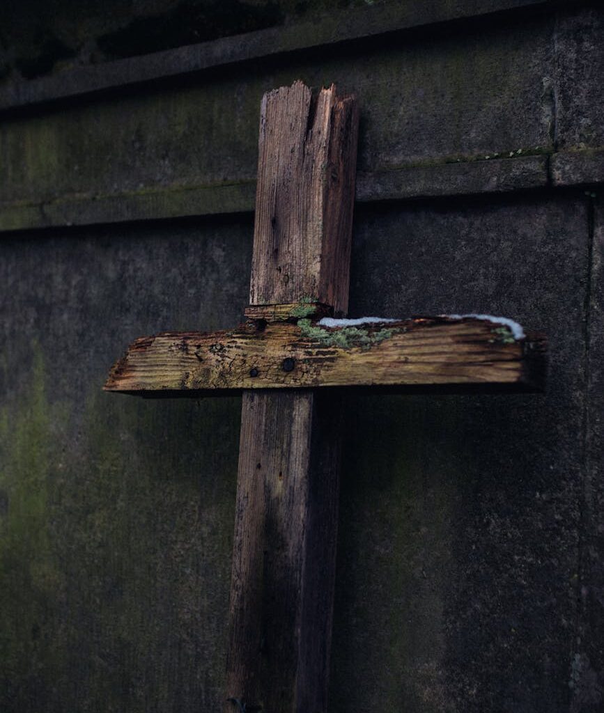 a broken wooden crucifix leaning on concrete